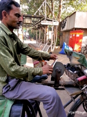 Man on bicycle sharpens knives on his grinding wheel